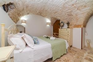 a bedroom with a white bed and a stone wall at Casa Nonno Seppo nel cuore del centro storico in Carovigno