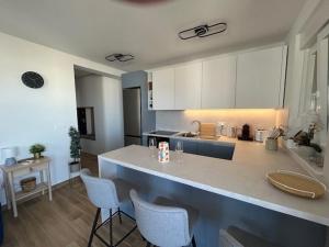a kitchen with white cabinets and a counter with chairs at Apartman Lejana in Mandre