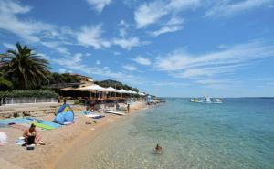 a beach with people laying in the water at Apartman Lejana in Mandre