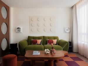 a living room with a green couch and a coffee table at Edgar Suites Levallois - Anatole France in Levallois-Perret