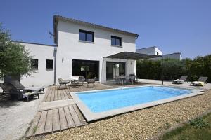 a swimming pool in front of a house at La Villa Plein Soleil in L'Isle-sur-la-Sorgue