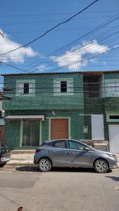 a silver car parked in front of a green building at Paulo in Guarujá +2 photos