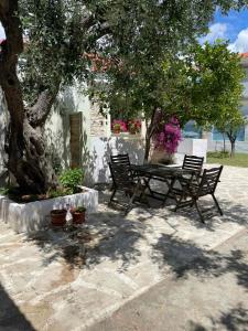 a picnic table and two benches under a tree at Mediterranean house in Skala Sotiros