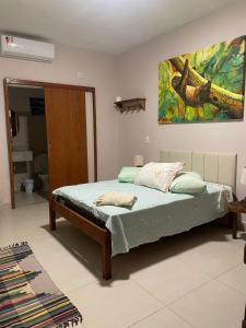 Un dormitorio con una cama y un cuadro en la pared. en Suítes Sacai - Privacidade e Conforto, en Conceição da Barra 9 fotos más