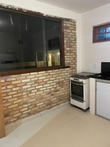 a kitchen with a brick wall and a window at Suítes Sacai - Privacidade e Conforto in Conceição da Barra +9 photos