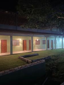 Una casa con puertas rojas y un patio por la noche. en Suítes Sacai - Privacidade e Conforto, en Conceição da Barra