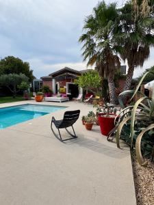 une chaise assise à côté d'une piscine bordée de palmiers dans l'établissement Une adorable chambre SUR les toits, à La Celle-sous-Gouzon