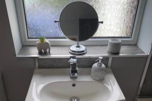 a bathroom sink with a mirror on top of it at Sands Lane Retreat - Cozy Bungalow in Hunmanby in Filey +8 photos
