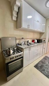 a kitchen with a stove and white cabinets at Appartement de Luxe Avec Jacuzzi Privé & Terrasse au Coeur de Marrakech in Marrakech