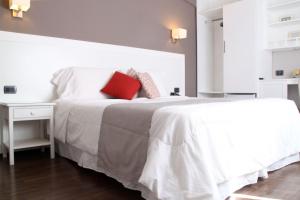 um quarto com uma cama branca e uma almofada vermelha em Hotel Milano em Punta del Este