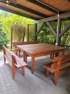 a wooden picnic table and benches on a patio at Pokoje Gościnne Grzegorz-2 in Białowieża