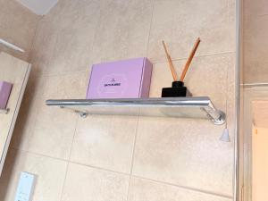 a book and chopsticks on a shelf in a bathroom at Lovely Room in Wembley Stadium in London