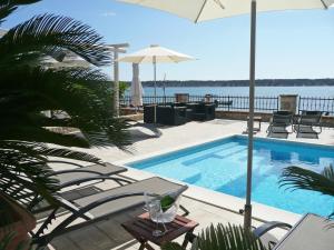 a swimming pool with chairs and an umbrella at Guest House Villa Papalina in Rab