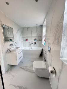 a white bathroom with a toilet and a sink at The Grand Royal Kilburn House - 4BR/3BR w Parking in London