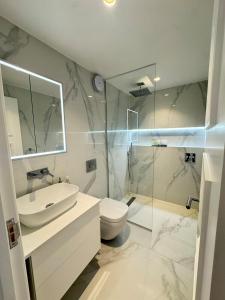 a bathroom with a sink and a toilet and a shower at The Grand Royal Kilburn House - 4BR/3BR w Parking in London