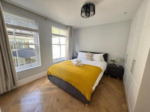 a bedroom with a bed with a yellow blanket at The Grand Royal Kilburn House - 4BR/3BR w Parking in London