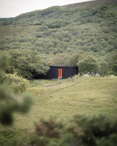 タンにあるThe Risingの畑にあるオレンジ色のドアが付いた黒い小屋