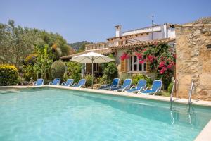 einen Pool mit blauen Stühlen und einem Sonnenschirm in der Unterkunft Villa Can Boseta by SunVillas Mallorca in Pollença
