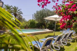 eine Gruppe von Stühlen und einem Sonnenschirm neben einem Pool in der Unterkunft Villa Can Boseta by SunVillas Mallorca in Pollença