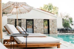a group of chairs and an umbrella next to a swimming pool at Samothraki Kaviri Boutique Residence in Samothraki