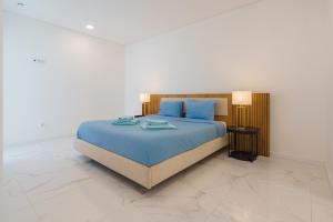 um quarto com uma cama com lençóis azuis e travesseiros azuis em Villa Arkadie with private pool na Lourinhã