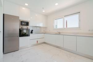 uma cozinha branca com armários brancos e uma janela em Villa Arkadie with private pool na Lourinhã