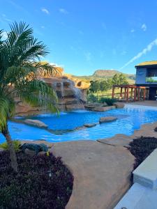 Una piscina con cascada y una palmera en un patio. en Pousada do Batata, en Capitólio