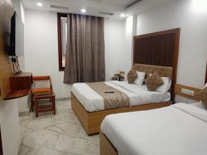 a hotel room with two beds and a television at Hotel C G Newly Built 2 Mins From Connaught Place and Railway Station & 5 Mins From VFS Shivaji Stadium Metro Station in New Delhi