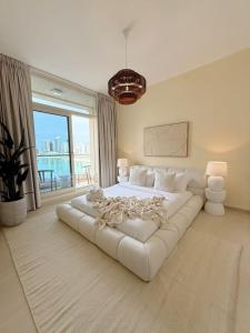 a large white bed in a room with a large window at Luxury Boho Retreat Serene Lagoon Views in Abu Dhabi