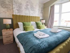 Un dormitorio con una cama grande con toallas. en Crescent Bay House, en Filey