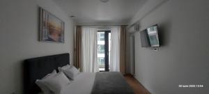 a bedroom with a bed with a television and a window at Apartament Derys in Năvodari