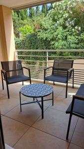 three chairs and a table on a balcony at LE SNOOKYBAY - Appartement Neuf - Classé 3 étoiles in Cavalaire-sur-Mer