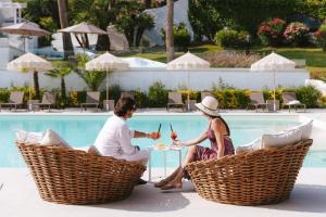 twee vrouwen zitten rond een tafel bij een zwembad bij Nu Aria Taunus Relais in Numana