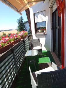 a balcony with chairs and a table and flowers at Haus Carmen in Falkenhain