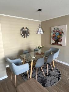 a dining room with a table and chairs and a clock at Arriendo apartamento diario in Puerto Montt