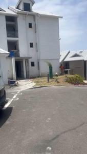 a white building with a parking lot in front of it at L'Astrolabe in Vieux-Fort