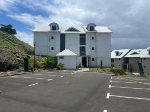 a large white building with a parking lot at L'Astrolabe in Vieux-Fort