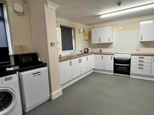 a kitchen with white cabinets and a washer and dryer at Atherley Rooms in Southampton