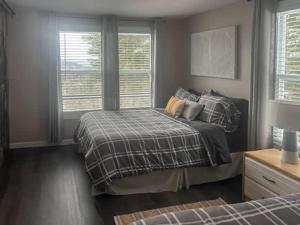 a bedroom with a bed and two windows at Cozy Chalet with Breathtaking Mountain View in Notre-Dame-Des-Bois