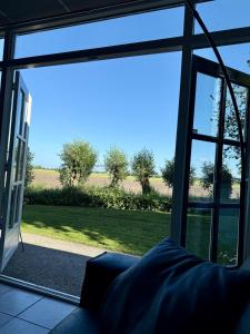 a living room with a large window looking out at a field at Holiday Home de Binnengouw in Hoogwoud