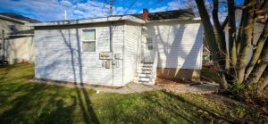 una pequeña casa blanca con una puerta en un patio en Downtown 2BR Gem: Near Soaring Eagle & Downtown, en Mount Pleasant