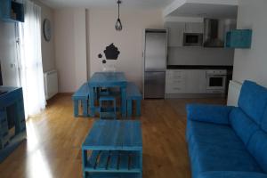 Una sala de estar con un sofá azul y una mesa. en Apartamento Turístico “El Yugo”, en Arguedas