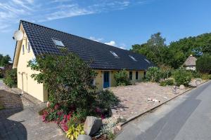 ein gelbes Haus mit schwarzem Dach und ein paar Blumen in der Unterkunft Ferienhaus für 3 Personen  2 Kinder ca 60 m in Neuenkirchen, Ostseeküste Deutschland Rügen in Neuenkirchen