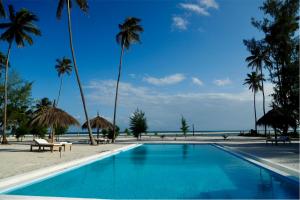 a swimming pool next to a beach with palm trees at Banja Amani Lodge Mafía Island in Mafia Island