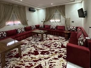 a living room with a red couch and a large rug at Appartements ELKHAIR in Tahannout