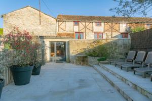 a patio with two chairs and a building at Gîte Lunaben-Maison en pierres avec piscine in Forges