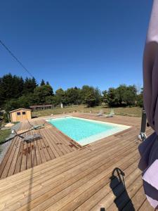 a wooden deck with a swimming pool on top of it at Gîte des chardreaux in Marval