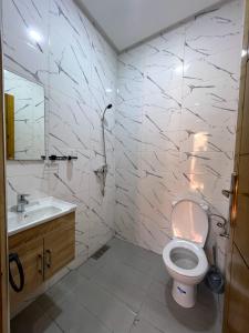 a white bathroom with a toilet and a sink at Appartements ELKHAIR in Tahannout +9 photos