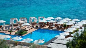 a pool with white umbrellas and chairs and the ocean at Villa Petit Lujo in Badia Gran