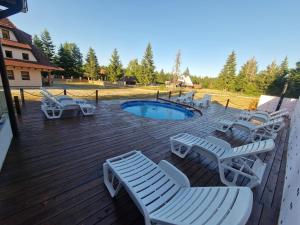 una terrazza in legno con sedie e una piscina di Vila Tri Srca a Beserovina